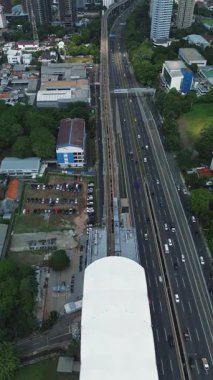 Yoğun bir otoyol kenarındaki MRT treninin yüksek açılı görüntüsü, kentsel altyapı ve ulaşımı gösteriyor.
