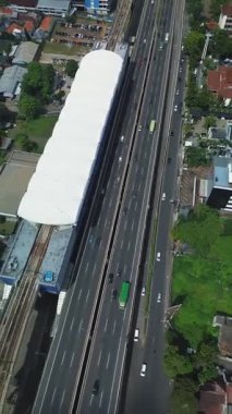 Bir MRT istasyonu ve akıcı trafiği olan bitişik otoyolun yukarıdan görünüşü. Görünür şehir manzarasını çevreleyen.