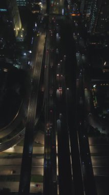 Gece otoyol trafiğinin yüksek açılı görüntüsü. Şehir ışıkları sahneyi aydınlatıyor.
