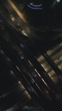 Gece otoyol kavşağının yukarıdan görünüşü. Birden fazla şeritte giden arabalar. Karanlık, aydınlık yollar.
