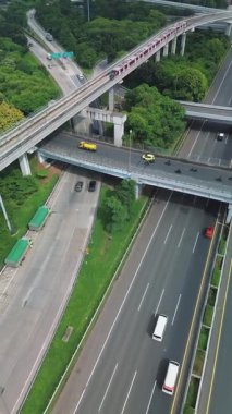 Jakarta 'nın LRT treninin yoğun bir otoyol kavşağının üstündeki yüksek bir raydan geçişinin havadan görüntüsü..