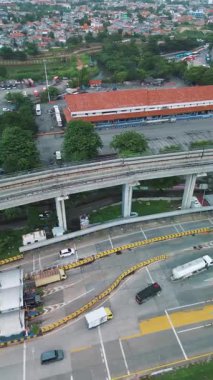 Otobanın yüksek açılı görüntüsü, yüksek tren rayları ve çevre kentsel alan. Yollarda araçlar görülüyor..