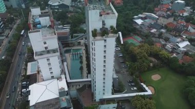 Apartman kompleksi, havuz, otopark ve çevre şehrin yüksek açılı insansız hava aracı görüntüleri. Yeşillik ve yerleşim alanları görülebilir.