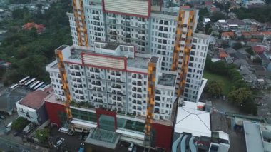 Büyük bir apartmanın, çevreleyen binaların ve yeşil bir alanın insansız hava aracı görüntüleri. Yüksek açılı görüş. DKI Jakarta, Endonezya - 31 Ocak 2025
