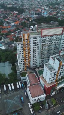 Apartman binalarının, etrafındaki şehirlerin ve park halindeki otobüslerin yüksek açılı drone görüntüleri. Yerleşim alanına bakan.