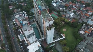 Apartman kompleksi, havuz, golf sahası ve çevre şehrin yüksek açılı insansız hava aracı görüntüleri. Yoldaki arabalar, görülebilir konut alanları..