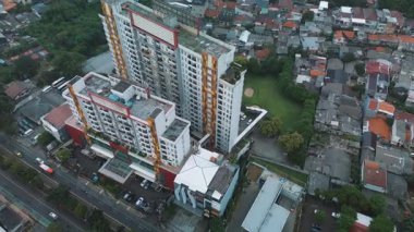 Modern bir apartmanın yüksek açılı drone görüntüsü, bitişik binalar, bir yol ve yemyeşil bir alan..