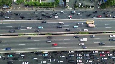 Yoğun otoyol trafiğini, arabaları, motosikletleri ve bir otobüsü yüksek açılı görüyor. Bir İHA 'dan havadan çekim.