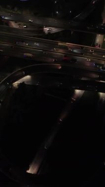 Gece otoyol kavşağının yukarıdan görünüşü. Arabalar ve kamyonlar sürüyor. Koyu arkaplan.