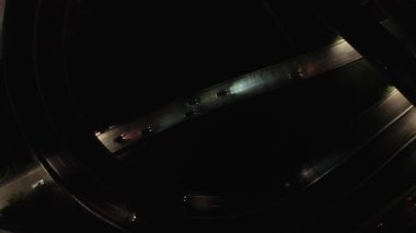 Gece bir otoyol kavşağında giden arabaların uzaktan kumandalı görüntüleri. Karanlık, aydınlık yollar.