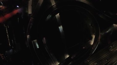 Gece karayolu kavşağının havadan görünüşü. Aydınlanmış yollarda giden arabalar. Koyu arkaplan.