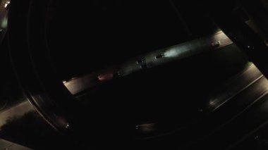 Gece bir otoyol kavşağında giden arabaların uzaktan kumandalı görüntüleri. Karanlık, aydınlık yollar.