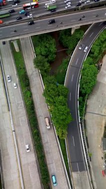 Yoğun trafik ile otoyol kesişiminin genel görüntüsü, arabaları, kamyonları ve çevresindeki yeşillikleri gösteriyor.