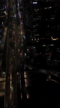 Yoğun trafik akışı ve şehir ışıklarını gösteren gece vakti bir otoyol manzarası. Yüksek açılı çekim.