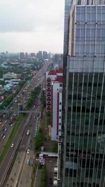 Modern gökdelenlerin, şehir trafiğinin ve yerleşim alanlarının yanındaki işlek bir otoyolun yüksek açılı görüntüsü.