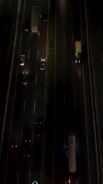 Geceleri otoban trafiğinin hava görüntüsü. Çok şeritli yolda giden arabalar ve kamyonlar. Tepeden çekim.
