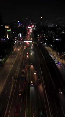 Geceleri otoban trafiğinin hava görüntüsü. Çok şeritli yolda giden arabalar. Arkaplanda şehrin ufuk çizgisi.