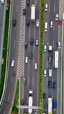 Yoğun otoyol trafiğinin insansız hava aracı görüntüsü. Arabalar, kamyonlar ve otobüsler birden fazla şerit boyunca hareket ederler..