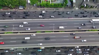 Yoğun otoyol trafiğinin insansız hava aracı görüntüsü. Arabalar, kamyonlar ve motosikletler birden fazla şerit boyunca hareket ederler..