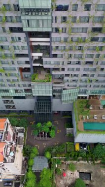 Yüksek açılı insansız hava aracı, verimli yeşillik ile modern bir otel binasının mimarisini ve çevresini gözler önüne seriyor..