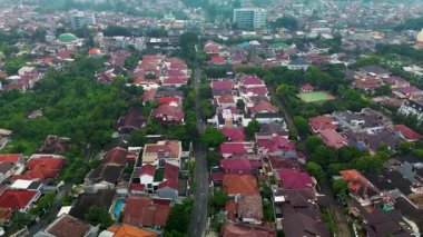 Evleri, yolları ve ağaçları olan bir yerleşim bölgesinin yüksek açılı insansız hava aracı görüntüsü. Sakin, puslu bir gün.