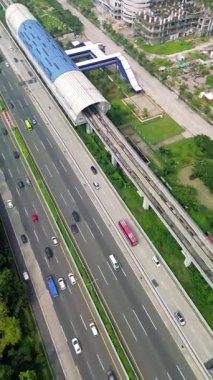Light Rail Transit (LRT) istasyonu, karayolu trafiği ve çevresinin yüksek açılı görüntüsü. Arabalar, otobüsler ve tren rayları görünür..
