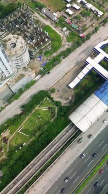 Bir Light Rail Transit (LRT) istasyonunun üstten çekimleri, çevre yol, park ve binalar. Otoyol boyunca arabalar hareket ediyor.