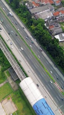 Light Rail Transit (LRT) istasyonu, bitişik otoyol ve çevreleyen yeşillik manzarası. Arabalar ve kamyonlar hareket halinde.