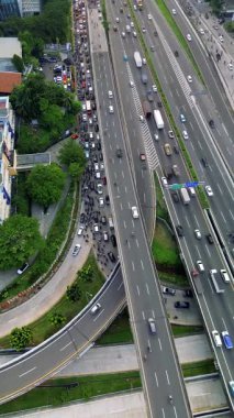 Yoğun trafik sıkışıklığı ve kavşağı olan yoğun bir otoyolun yüksek açılı insansız hava aracı görüntüsü. Araçlar yavaş hareket ediyor.