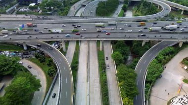 Yoğun bir otoyol kavşağının yüksek açılı görüntüsü. Çeşitli araçlar, ağaçlar ve bir nehir. Hava görüntüsü.