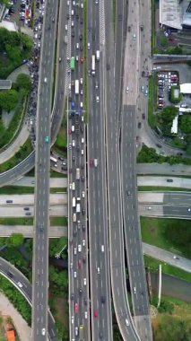 Yoğun otoyol kesişiminin insansız hava aracı görüntüleri, çeşitli araçları ve çevresindeki manzarayı gösteriyor.