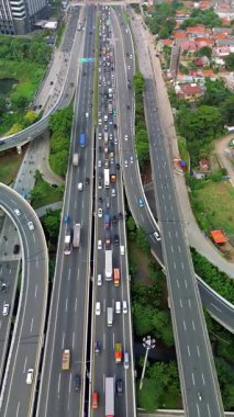 Yoğun otoyol trafiğinin, arabaların, kamyonların ve motosikletlerin yüksek açılı görüntüsü. İHA atışı, şehir ayarı.