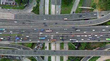 Yoğun trafik akışına sahip çok şeritli bir otoyol kavşağının üstten drone görüntüsü. Arabalar, kamyonlar, otobüsler..