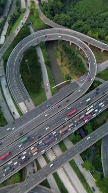 Yoğun trafik akışıyla karışık bir otoyol kavşağının yukarıdan çekimi. Yeşiller yemyeşil.