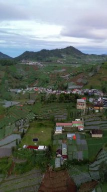 Bu görüntüler teraslı tarlaların ve dağ vadisindeki küçük bir köyün havadan görünüşünü gösteriyor. Kamera yavaşça aşağı doğru döner ve alanların düzenini ortaya çıkarır..
