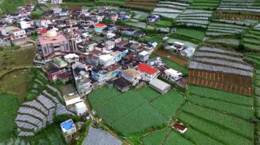 Teraslı tarlaların arasına gizlenmiş bir köyü görüntüler. Altın kubbeli bir cami göze çarpıyor. Kamera yavaşça döner, manzarayı gösterir..