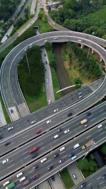 Yoğun trafik akışına sahip, yemyeşil bir otoban kavşağının yüksek açılı görüntüsü.