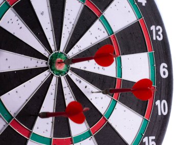 Dart tahtasının ortasına isabet eden kırmızı dartların beyaz arka planda izole edilmiş yan görüntüsü. Hassasiyeti, odaklanmayı, iş stratejisini, liderliği ve hedefe yönelik başarıyı simgeleyen.