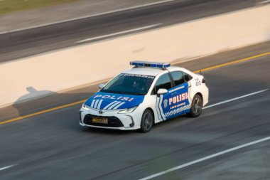 Malang, Endonezya, 20 Haziran 2024. Bir Endonezya polis arabası (Toyota Corolla Altis V), MalangPandaan otobanında güvenliği sağlamak için öğleden sonra devriyesi yürüttü. Bulanık