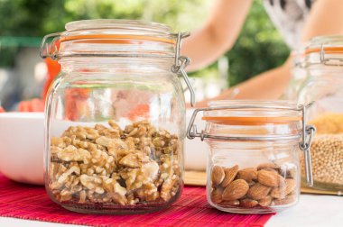 Mutfak masasında farklı ürünlerin olduğu kavanozları tutan kadın. sağlıklı beslenme, diyet, diyet ve sağlıklı gıda konsepti.