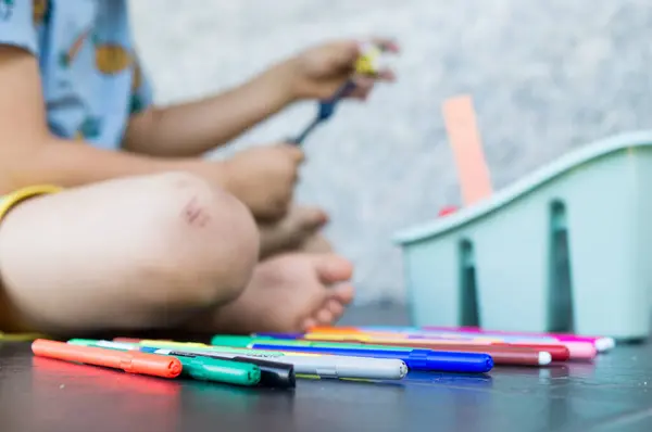 Küçük kız renkli bir tebeşir çiziyor.