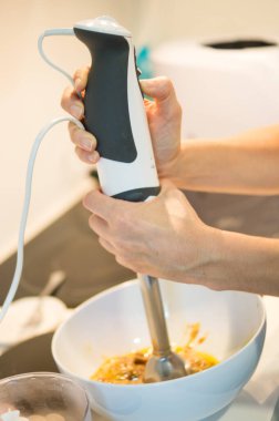 Kadın mutfakta elektrikli mikser yapıyor.