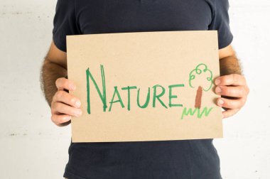 Üzerinde bir tabela ve çevresel mesaj olan lacivert tişört giyen bir adam.