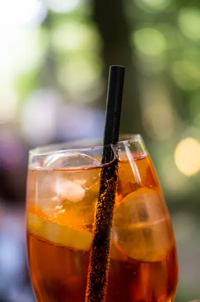 Arka planda Bokeh 'in olduğu açık hava partisinde bir bardak Aperol Spritz.