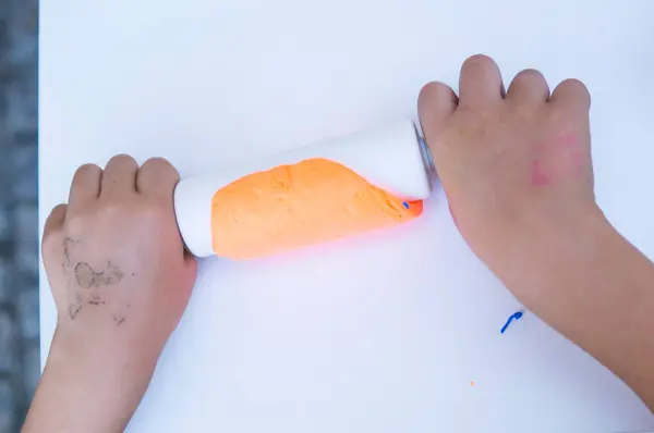 Çocuk elleri bir fırça ve bir işaret kağıdının arka planında