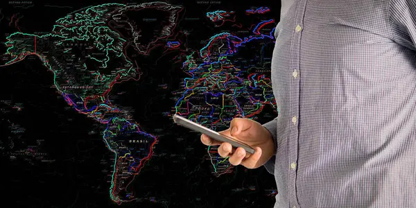 Cep telefonu ve arka planda bir neon dünya haritası olan bir adam küresel bağlantı kavramı olarak