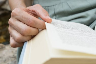 Kadın elleri kitap okuyor.