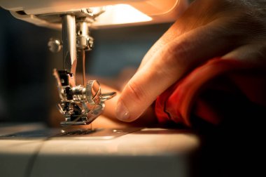 Adamın elinde dikiş makinesi var.