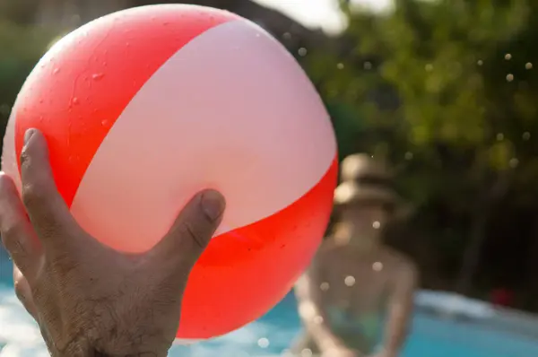 Havuzda yüzen şişme balon tutan adam..