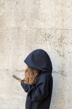 Cep telefonuna bağımlı yalnız bir gencin yan görüntüsü.